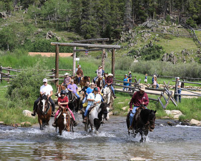 Riders on horseback cross a creek at the Paradise Ranch