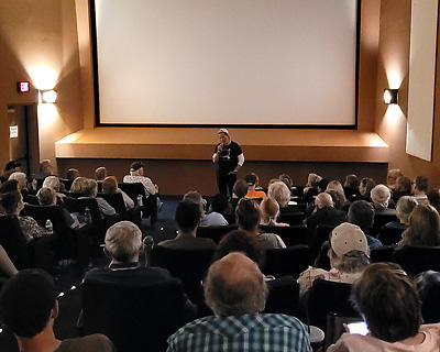 A Martinez stands in the front of a movie theater answering an audience question.